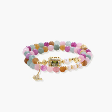 Stretchable bracelet with pastel gemstone beads, freshwater pearls, gold centerpiece and butterfly charm on cream background