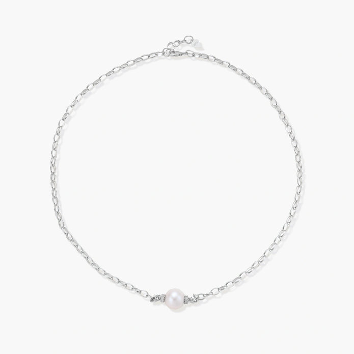 Dainty rhodium-plated silver chain necklace with centered 10mm freshwater pearl and crystal accents on cream background
