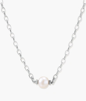 Dainty rhodium-plated silver chain necklace with centered 10mm freshwater pearl and crystal accents on cream background