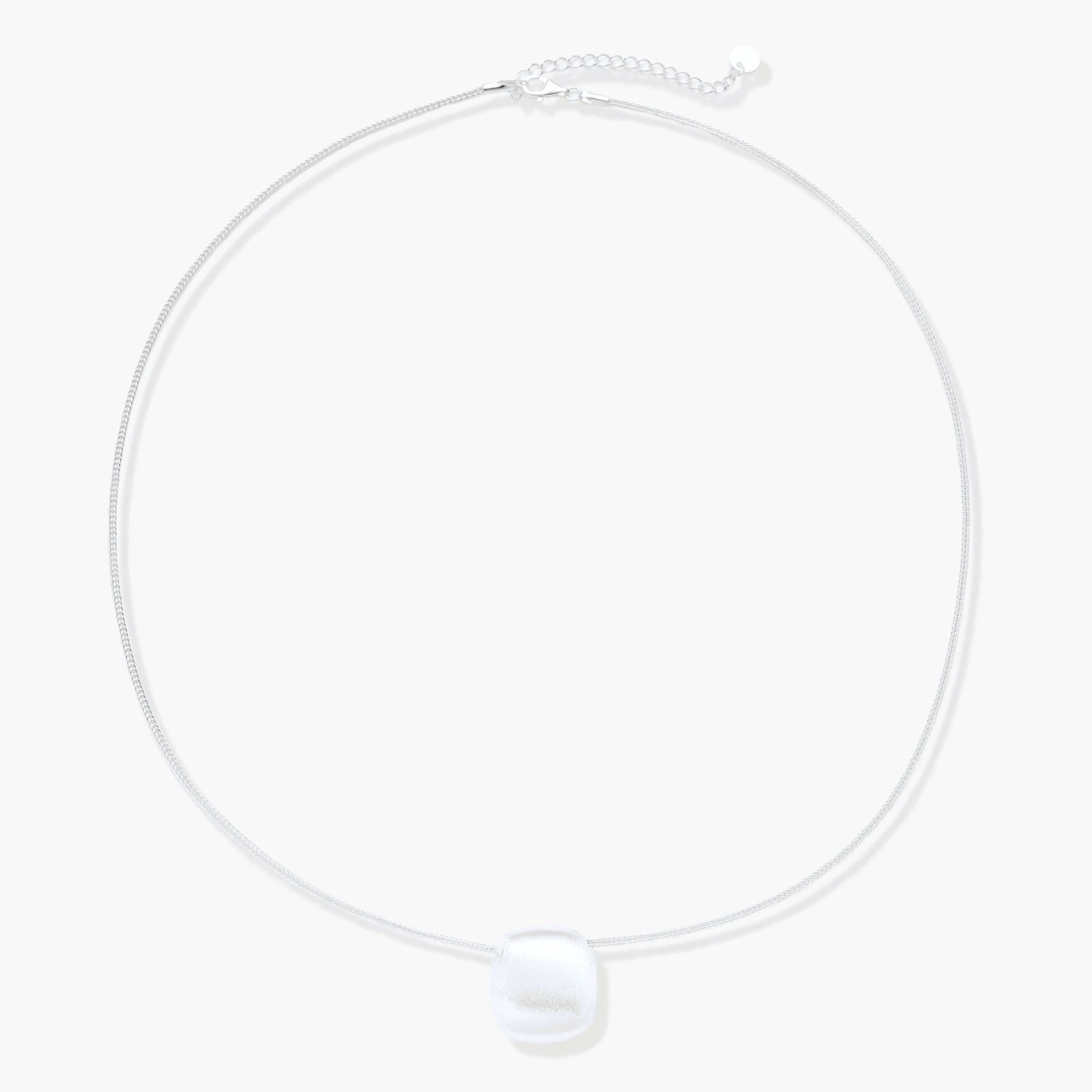 Minimalist brushed sterling silver dome pendant on delicate chain against cream background, showing matte textured finish