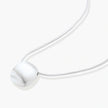 Minimalist brushed sterling silver dome pendant on delicate chain against cream background, showing matte textured finish