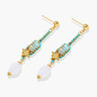 Gold-plated dangle earrings with turquoise threading, star charms, and white pearl beads against cream background.