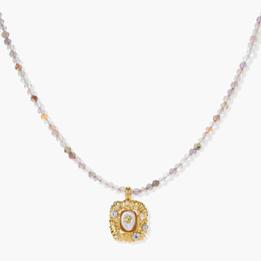Ornate gold-plated pendant necklace with multicolored gemstone beads in purple, pink and clear tones on white background