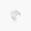 Wide sterling silver cuff ring with flowing wave patterns creating dimensional texture against cream background