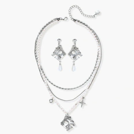Ornate silver-toned masquerade mask jewelry set featuring rhinestone details and pearl drop earrings on white background.