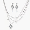 Ornate silver-toned masquerade mask jewelry set featuring rhinestone details and pearl drop earrings on white background.