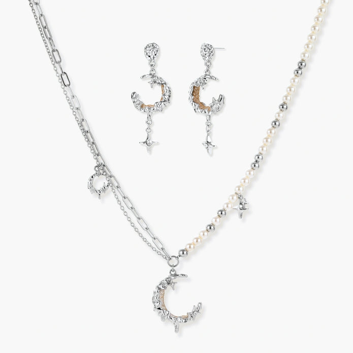 Mixed-metal jewelry set featuring layered necklaces with crescent moon pendant and pearl beads, plus matching star-drop earrings.