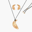 Gold-toned crescent moon pendant with textured surface on black adjustable cord, displayed with matching crescent earrings