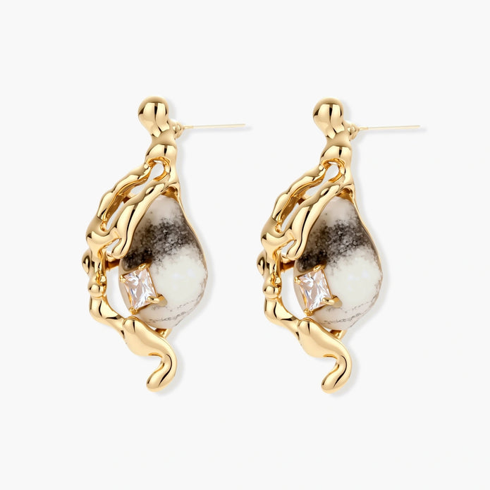 Close-up of metallic dragon-wrapped earrings with marbled resin stones on white background