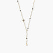 Y-shaped gold-plated necklace with white and gray freshwater pearls on cream background, showing adjustable drop design.