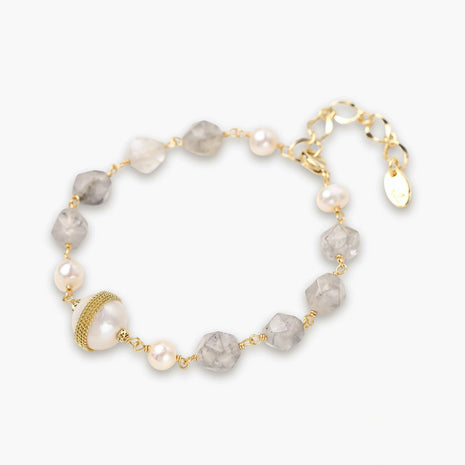 Bracelet with cloudy quartz beads, freshwater pearls, and gold-wrapped baroque pearl centerpiece on white background.