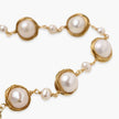 Gold wire-wrapped freshwater pearl bracelet with alternating pearl sizes on cream background, adjustable length