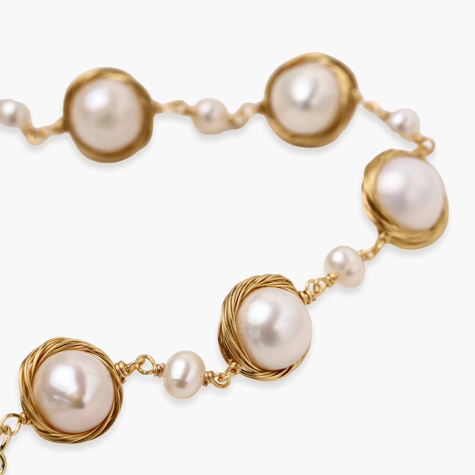Gold wire-wrapped freshwater pearl bracelet with alternating pearl sizes on cream background, adjustable length
