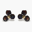 Dark iridescent baroque pearls arranged in flower pattern with 18K gold-plated center on cream background.