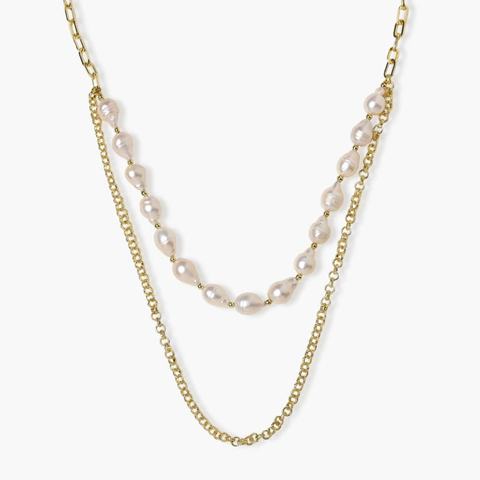 Layered gold chain necklace with organic baroque freshwater pearls and adjustable length on cream background
