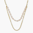 Layered gold chain necklace with organic baroque freshwater pearls and adjustable length on cream background