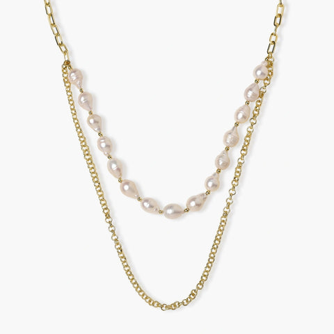Layered gold chain necklace with organic baroque freshwater pearls and adjustable length on cream background