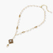 Y-shaped necklace with freshwater pearls, gold filigree stations, and ornate diamond-shaped centerpiece with pearl drop
